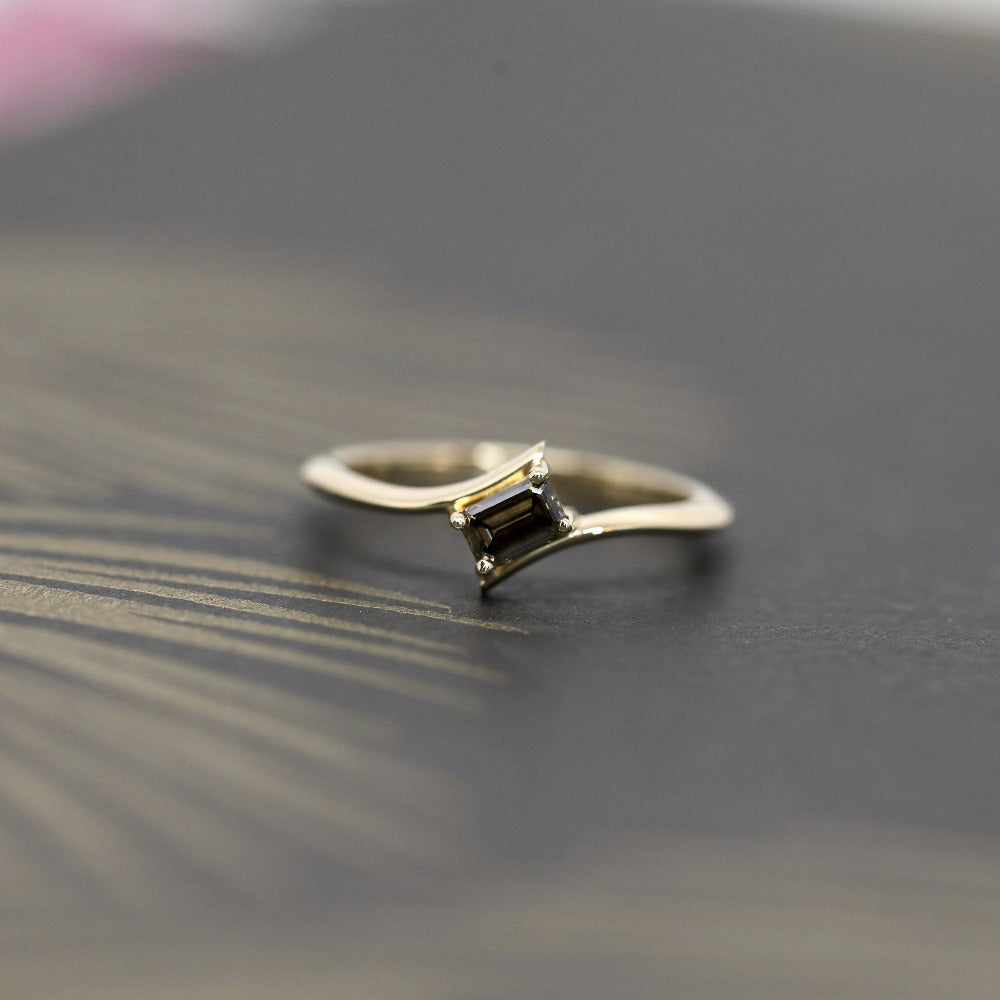Kink Baguette Chocolat Diamond Ring in yellow gold featuring a twisted band and a baguette-cut chocolate diamond by Bena Jewelry photographed on a dark background.