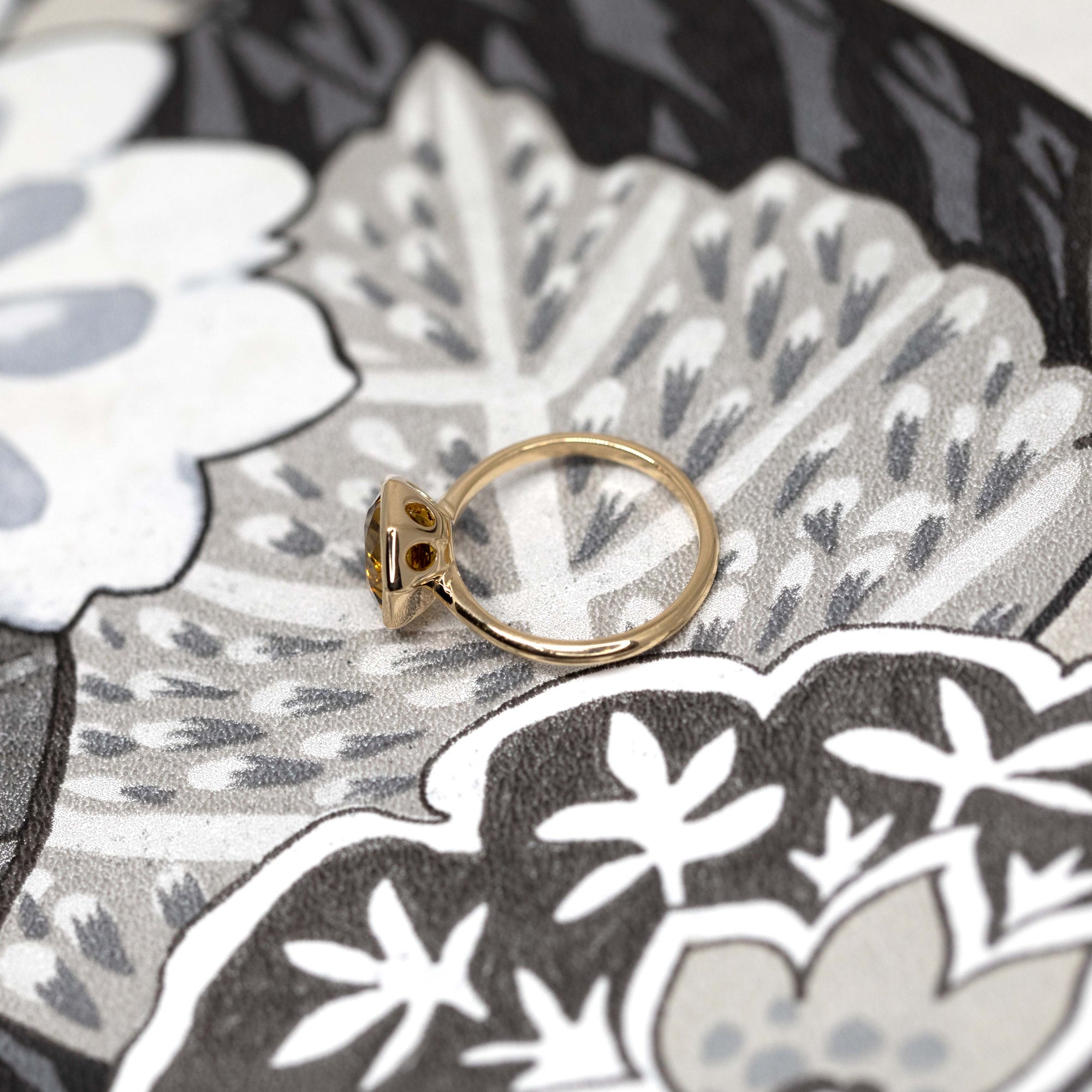 Fireball Citrine ring in a tilted angle on white background – A geometric hexagonal citrine with a fiery yellow-orange hue, set in polished yellow gold. Designed by Bena Jewelry in Montreal.