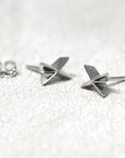 Cross Gold Studs in white gold by Bena Jewelry showcasing a sleek cross design with sharp edges, photographed on a soft pastel background, fine unisex jewelry custom-made in Montreal.