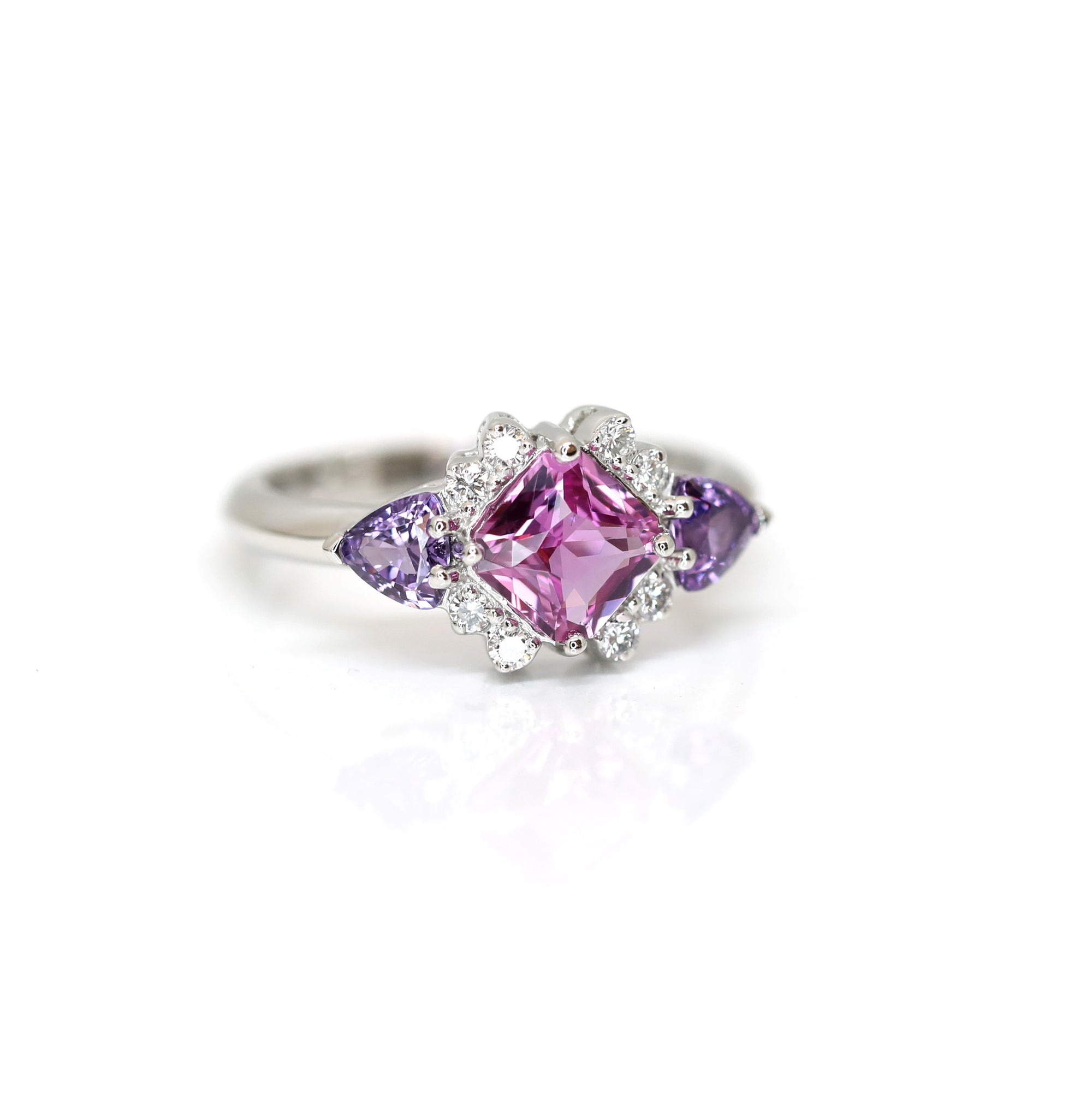 front view of purple and pink sapphire square shape and trillon cut gemstone with extra bright round diamond custom made in montreal by bena jewelry at ruby mardi on a white background