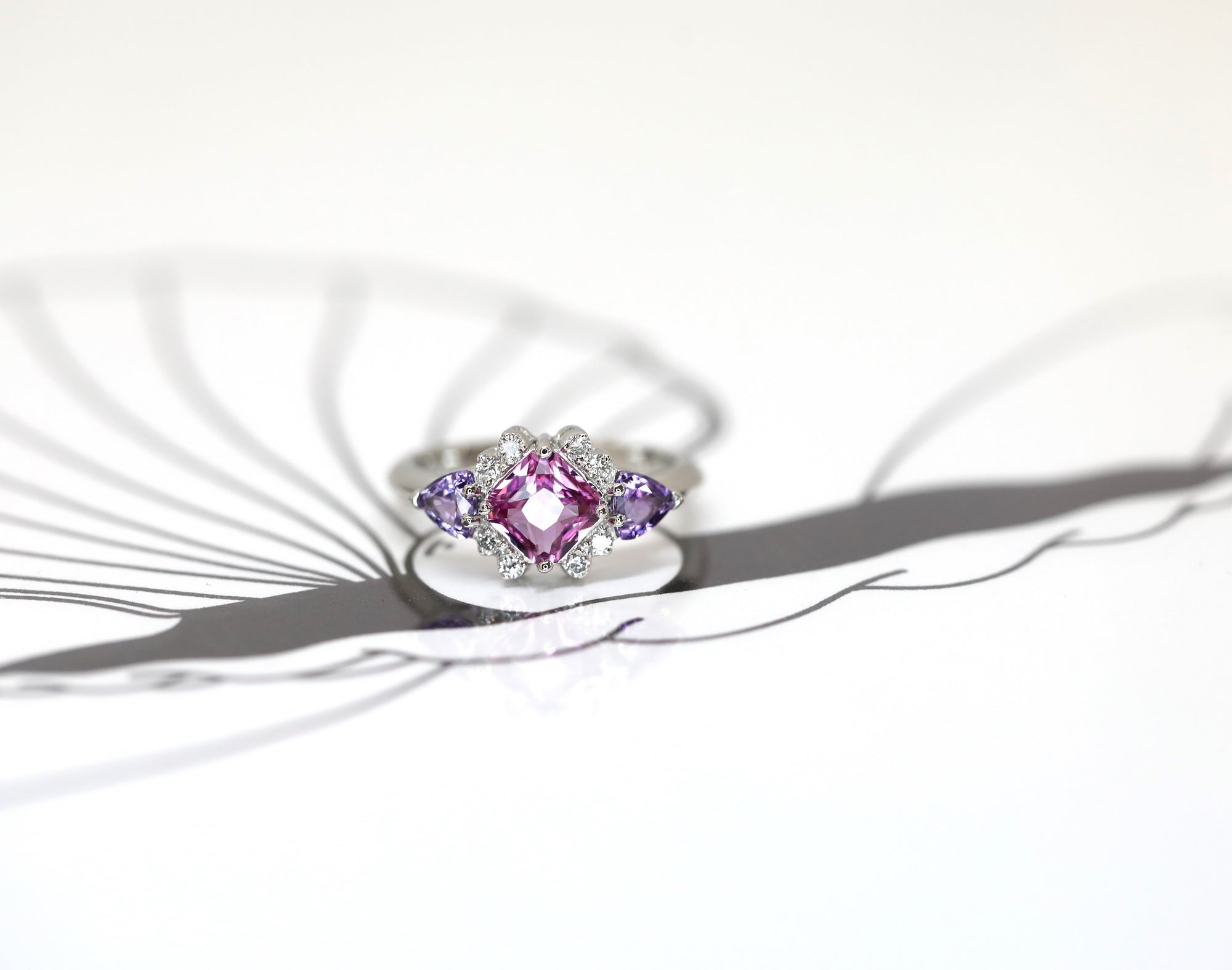 front view square shape pink sapphire and trillon shape purple gemstone diamond platinum custom made ring on white background