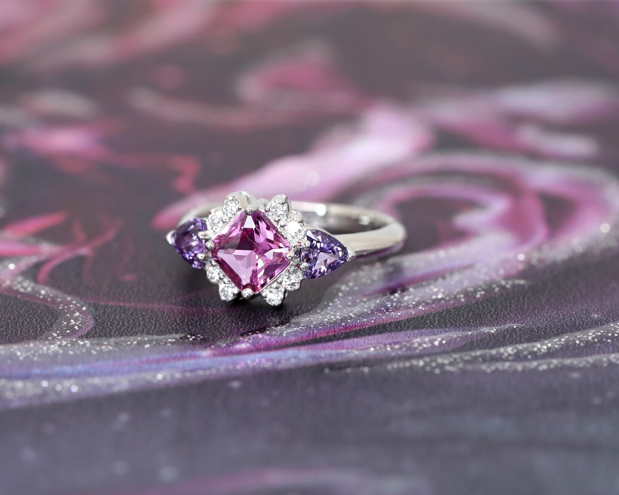 side view of purple pink sapphire square shape and trillon diamond platinum ring custom made in montreal by bena jewelry designer at ruby mardi on a dark multi color background