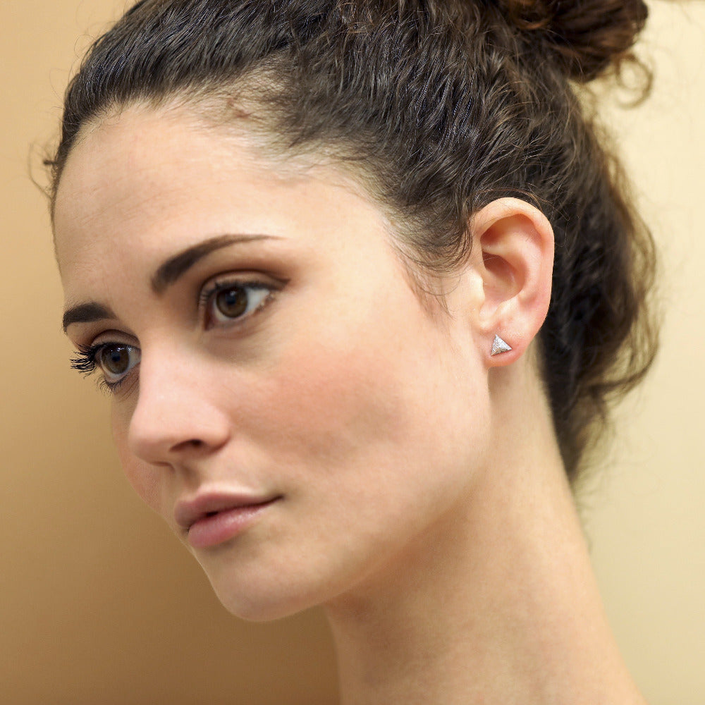 A woman wearing Delta Diamond Studs, illustrating the minimalist yet striking appeal of these white gold earrings with diamonds. Made in Montreal, Canada.