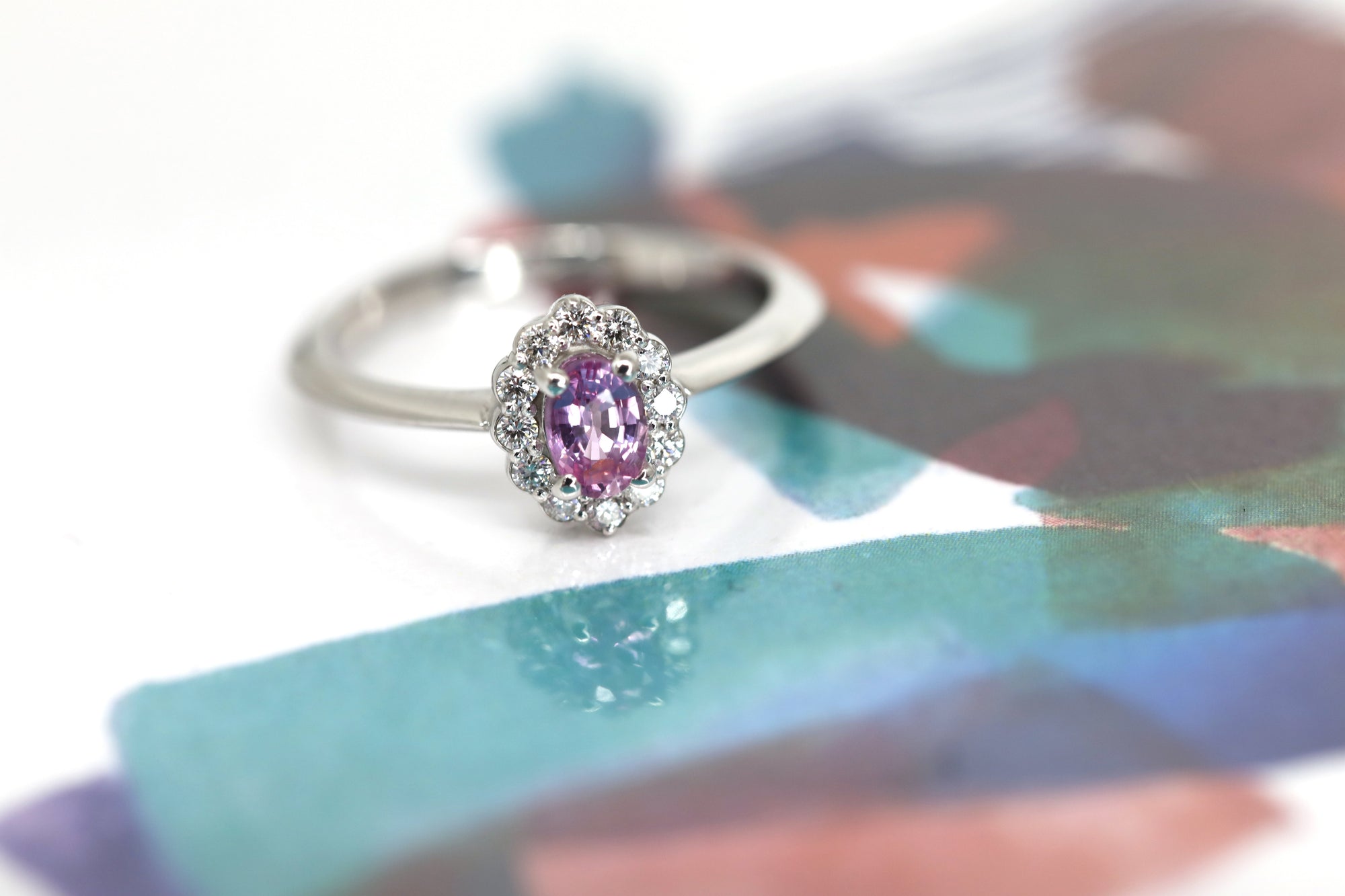 Bridal ring in white gold with an oval pink sapphire and shimmering diamond halo, designed and custom-crafted by Bena Jewelry in Montreal.