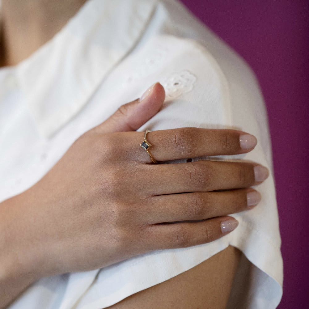 Close-up of a woman’s hand wearing the Kink Baguette Chocolat Diamond Ring in yellow gold, featuring a unique baguette-cut chocolate diamond, custom-made by Bena Jewelry in Montreal.