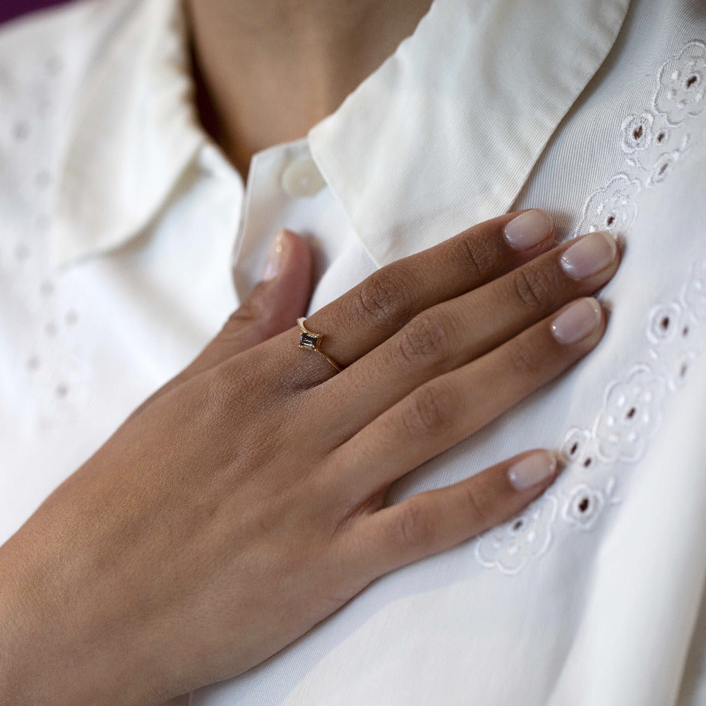 Detailed view of the Kink Baguette Chocolat Diamond Ring with a twisted yellow gold band and a chocolate diamond, handcrafted by Bena Jewelry, worn on a woman’s hand.
