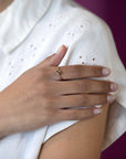 Yellow gold Kink Baguette Chocolat Diamond Ring by Bena Jewelry, showcasing a modern twisted band and a baguette-cut brown diamond in a close-up on a woman’s hand.