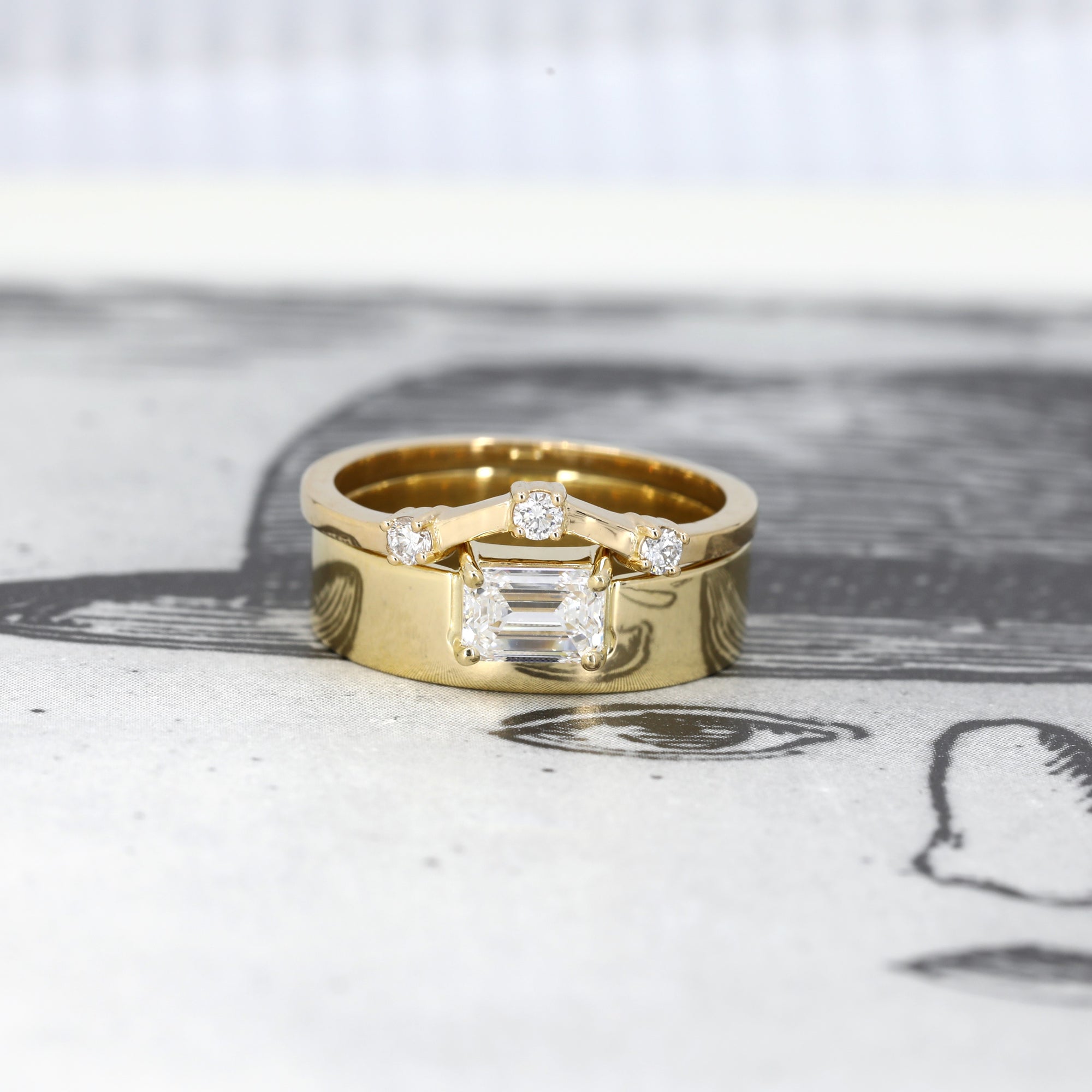 Yellow gold engagement ring with a sleek emerald-cut diamond and wide band. Unique fine jewelry by Bena Jewelry, crafted in Montreal, Canada.