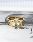Yellow gold engagement ring with a sleek emerald-cut diamond and wide band. Unique fine jewelry by Bena Jewelry, crafted in Montreal, Canada.