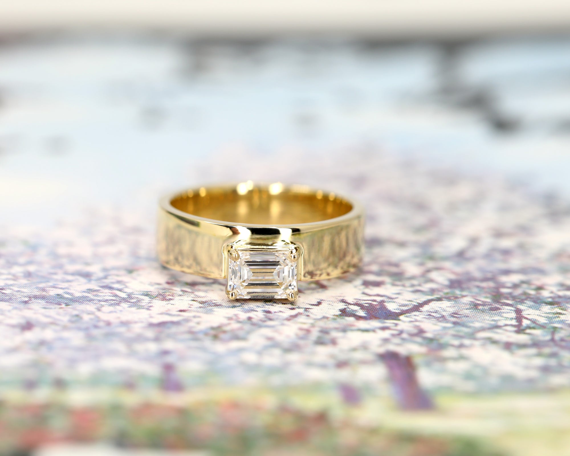 Modern yellow gold engagement ring with a bold emerald-cut diamond. Designed with a substantial gold band by Bena Jewelry, handcrafted in Montreal, Canada.