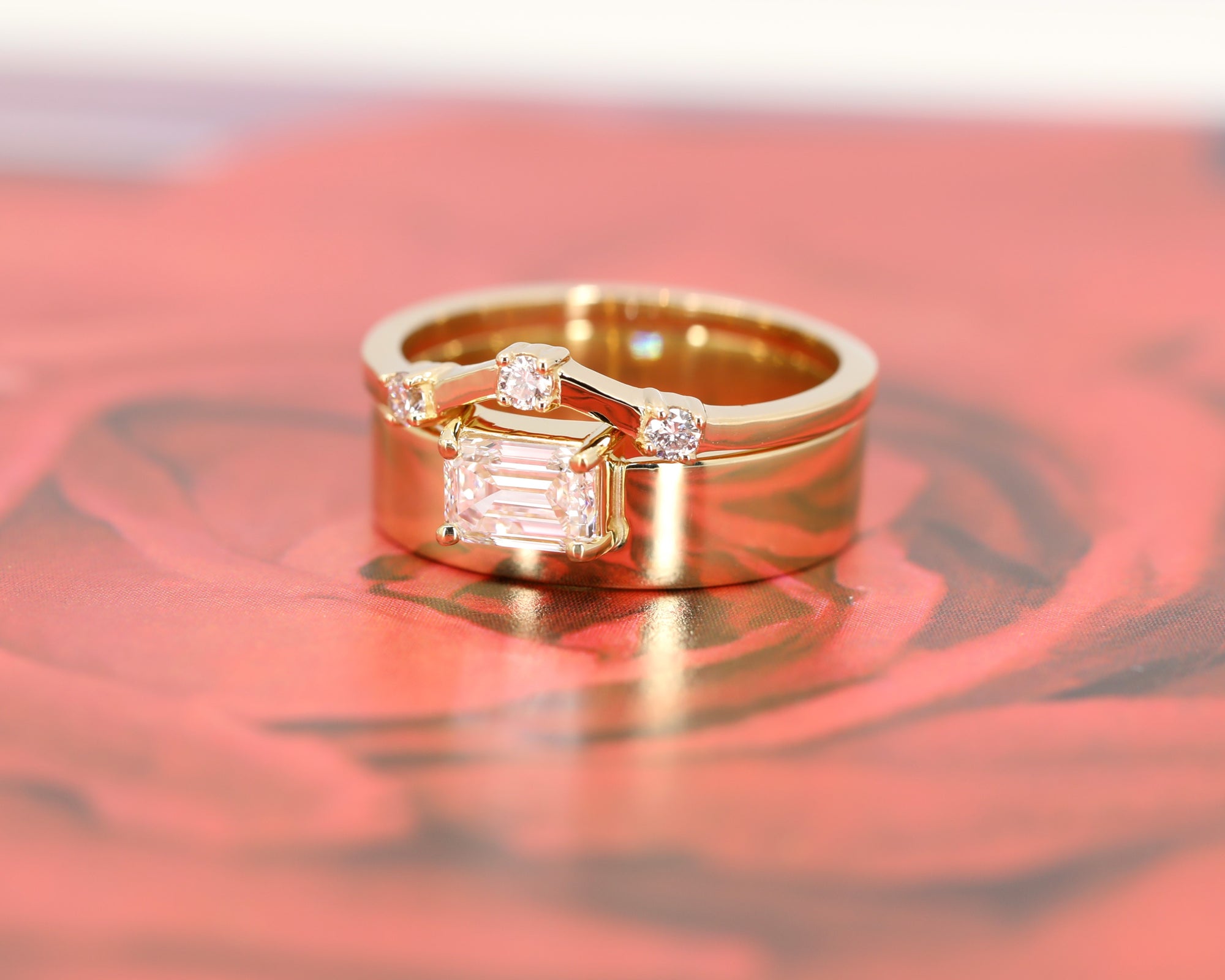 Yellow gold ring with a striking emerald-cut diamond and a wide gold band. A modern statement engagement ring by Bena Jewelry, Canadian designer.