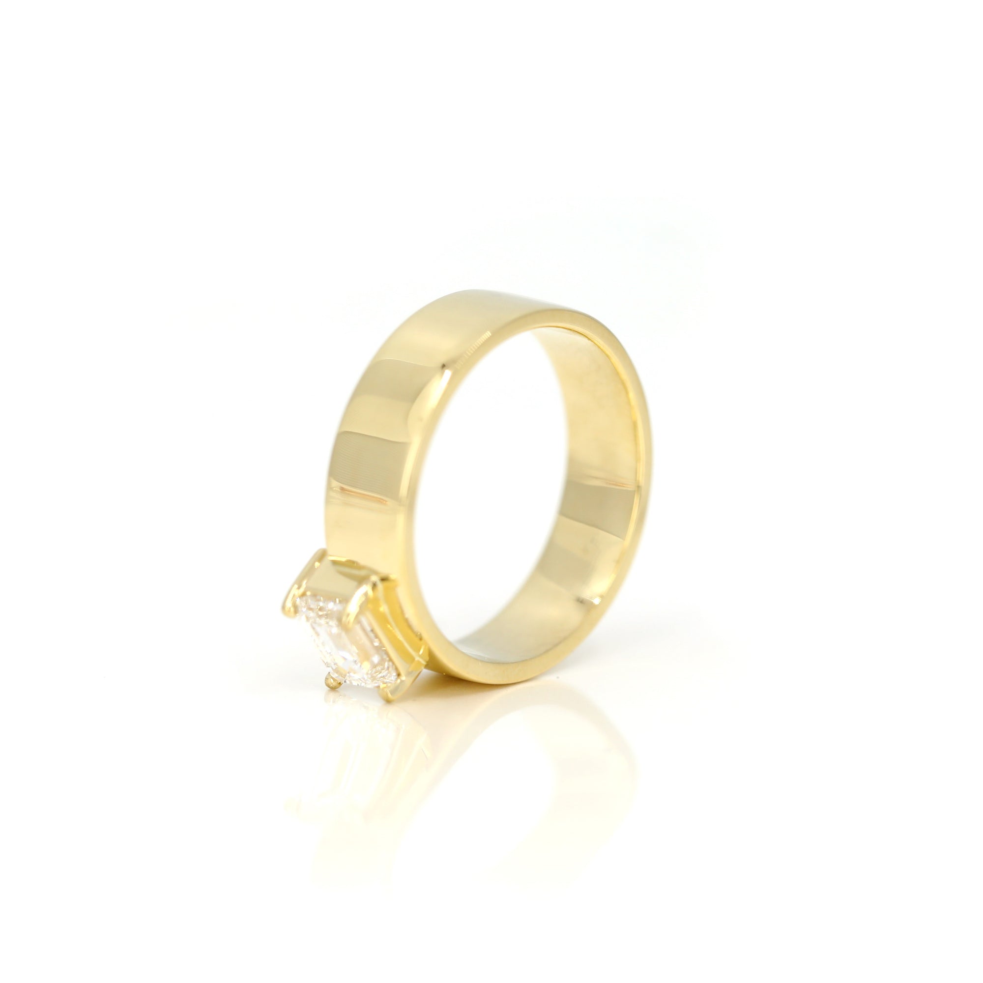 Edgy yellow gold engagement ring showcasing an emerald-cut diamond and a substantial gold design. A fine jewelry piece by Bena Jewelry, made in Montreal.