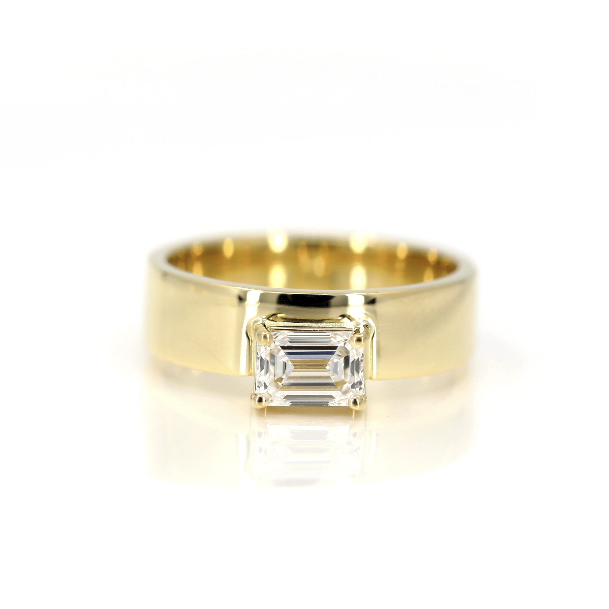 Bold yellow gold engagement ring with an emerald-cut diamond and a substantial gold band. Modern and edgy design by Bena Jewelry, made in Montreal, Canada.