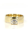 Bold yellow gold engagement ring with an emerald-cut diamond and a substantial gold band. Modern and edgy design by Bena Jewelry, made in Montreal, Canada.