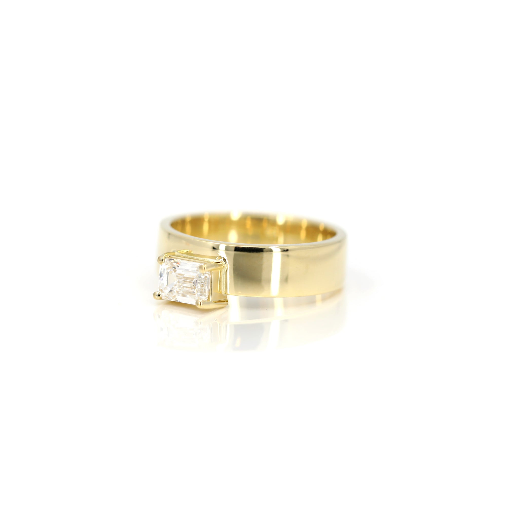 Wide yellow gold band with a sophisticated emerald-cut diamond centerpiece. A bold and modern design by Montreal-based Bena Jewelry.