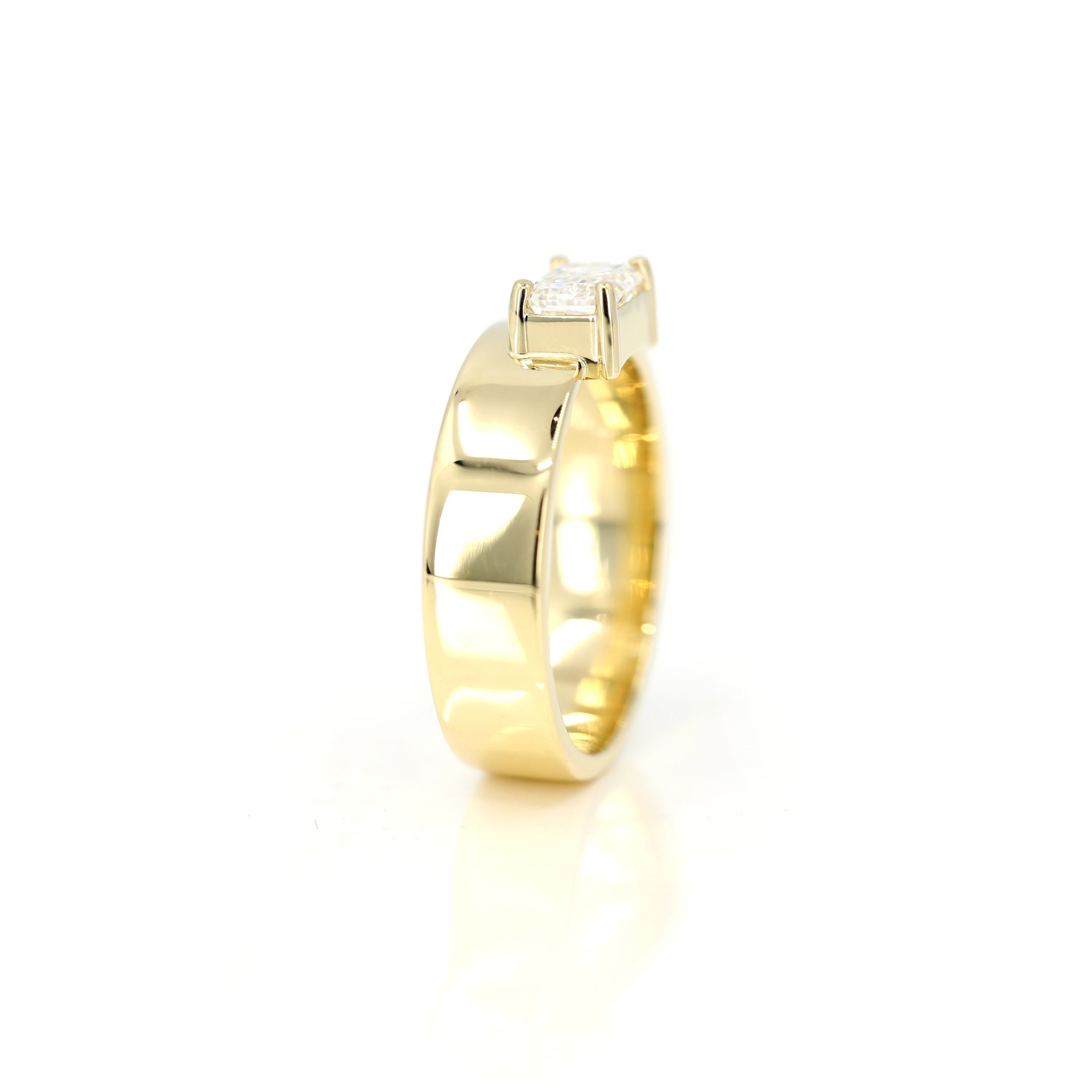 Luxurious yellow gold ring with an emerald-cut diamond and bold design. A statement engagement ring by Bena Jewelry, handcrafted in Montreal.