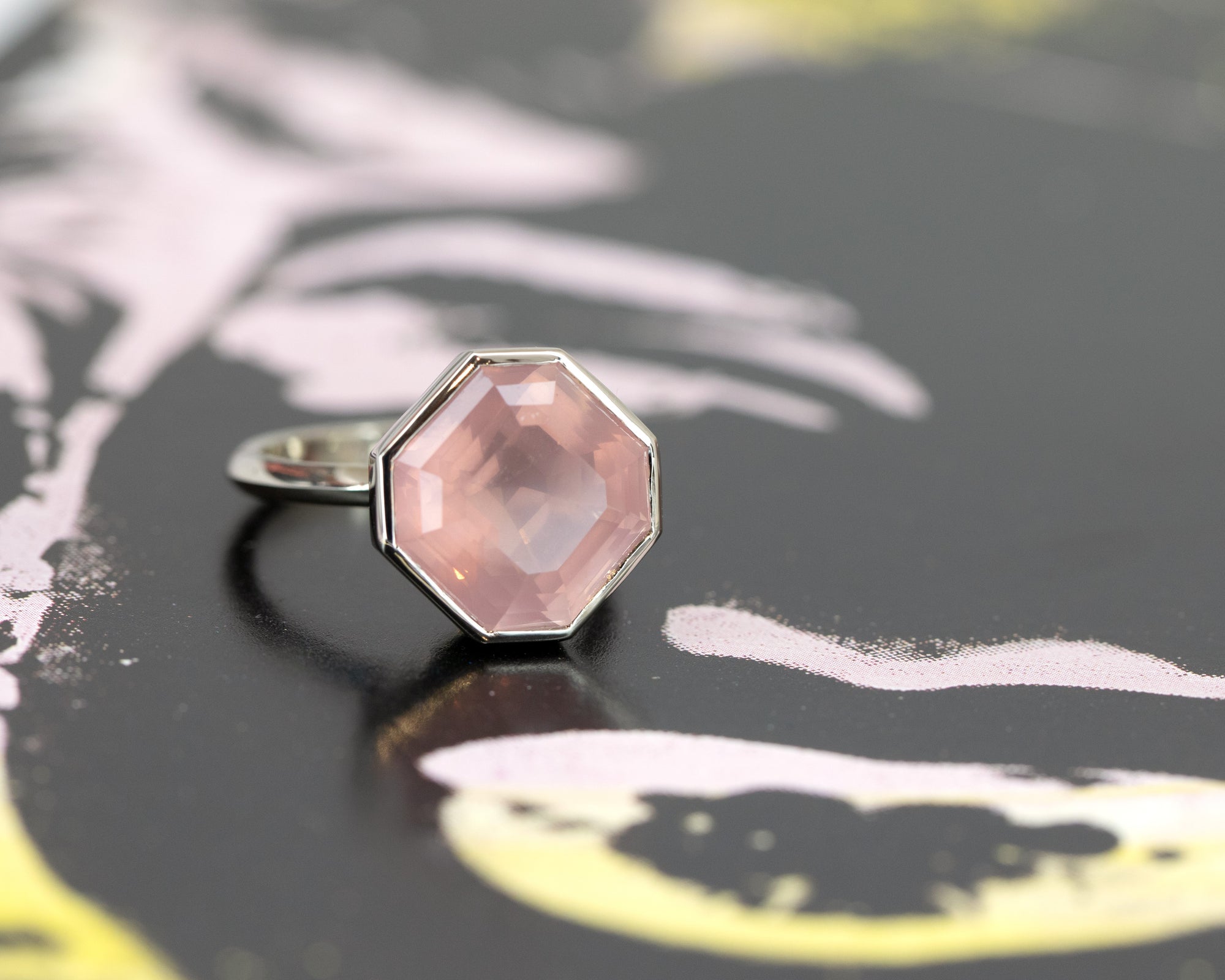 Front view of white gold ring with a translucent octagon-cut rose quartz, designed by Bena Jewelry, displayed on a black matte background, bespoke statement jewelry from Canada.