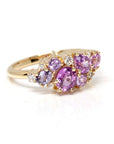 The Avalanche Pink Sapphire Ring against a dark background, emphasizing the vibrant sapphires and diamonds in the warm yellow gold setting. Designed by Bena Jewelry, Montreal, Canada.