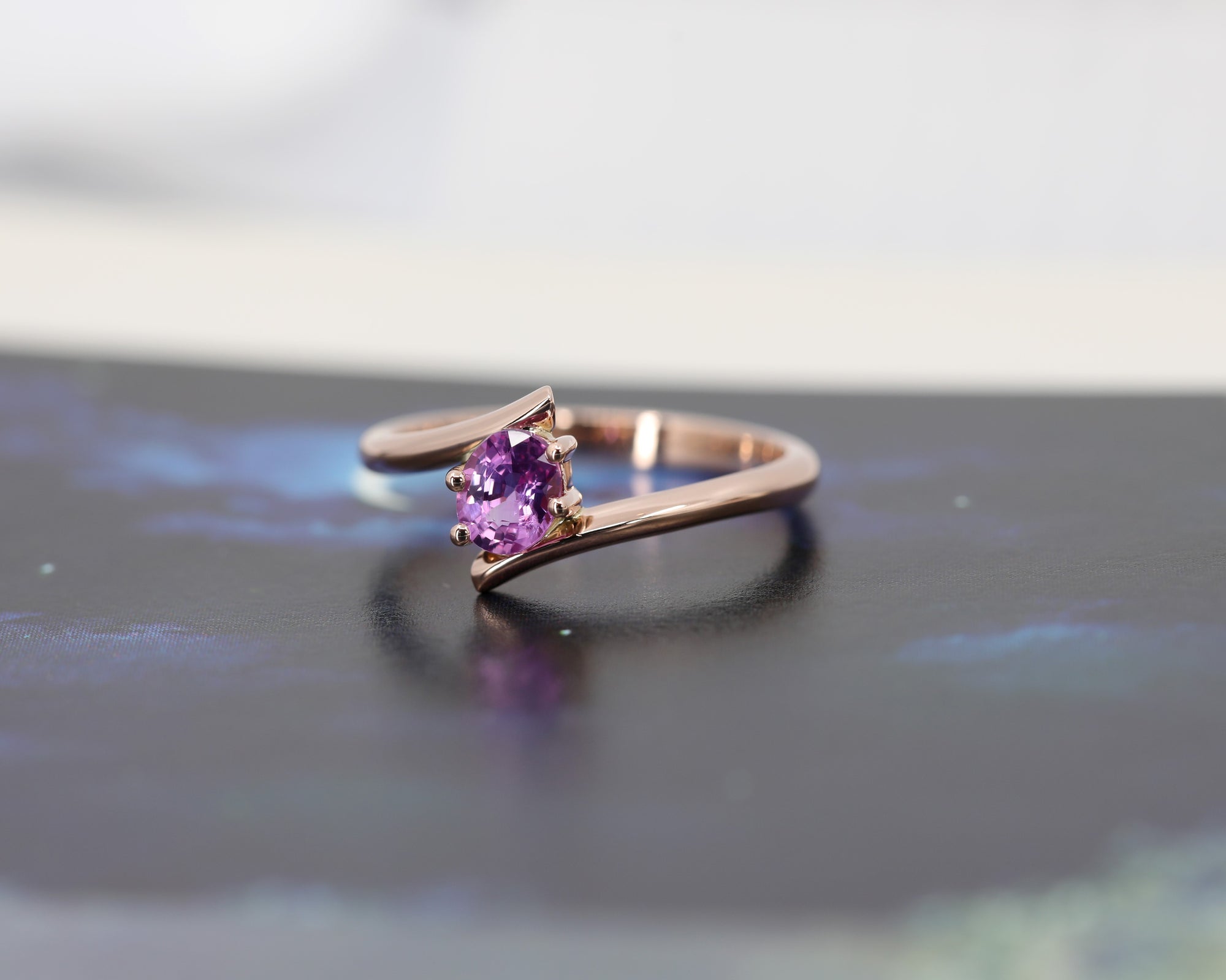 front view of pink sapphire engagament ring cusotm made in montreal by bena jewelry on black and white background