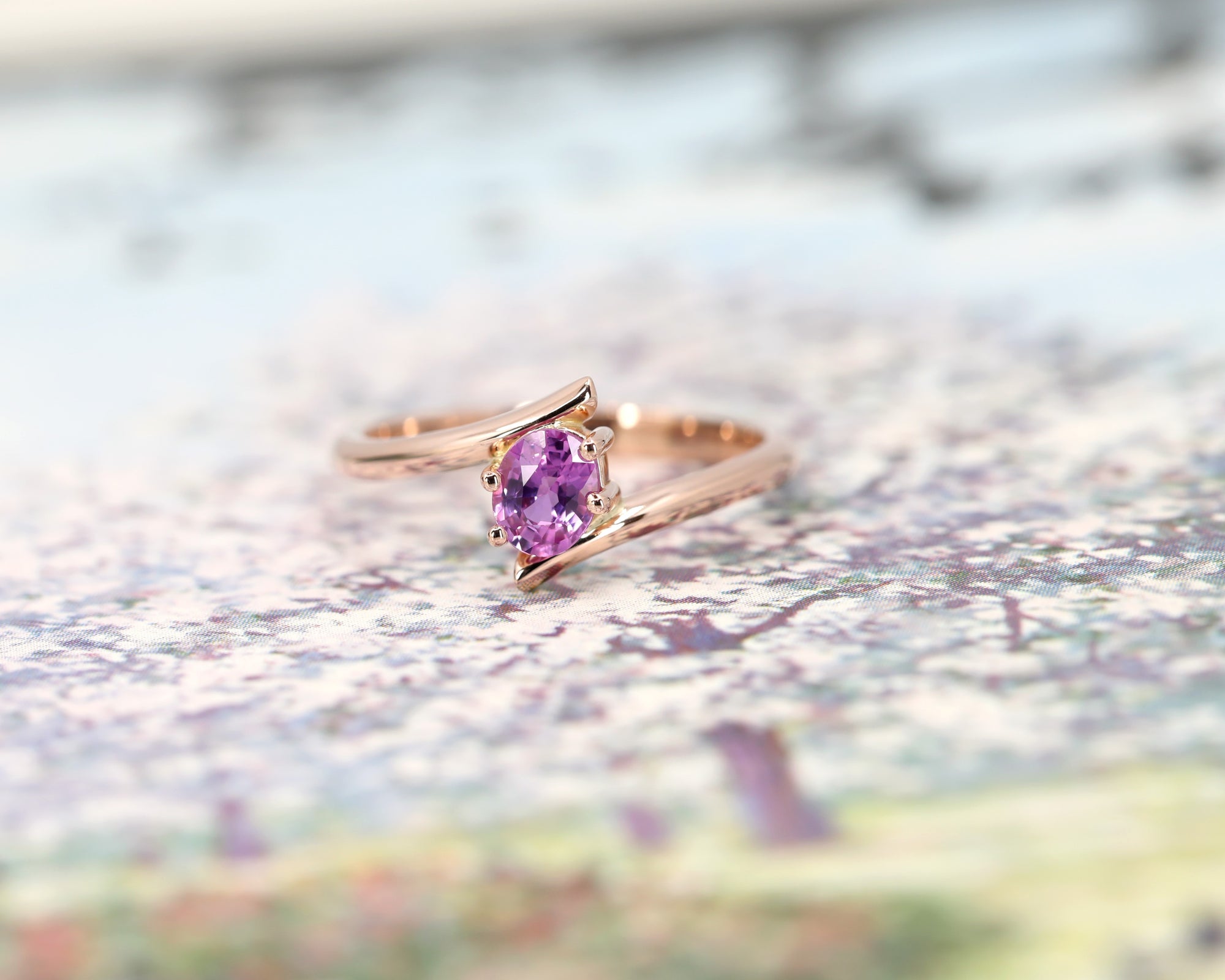 front view of pink sapphire custom made engagement ring made in montreal by bena jewelry on multi color background