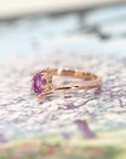 side view of bena jewelry kink ring made in montreal in rose gold with pink sapphire natural gemstone on multi color background