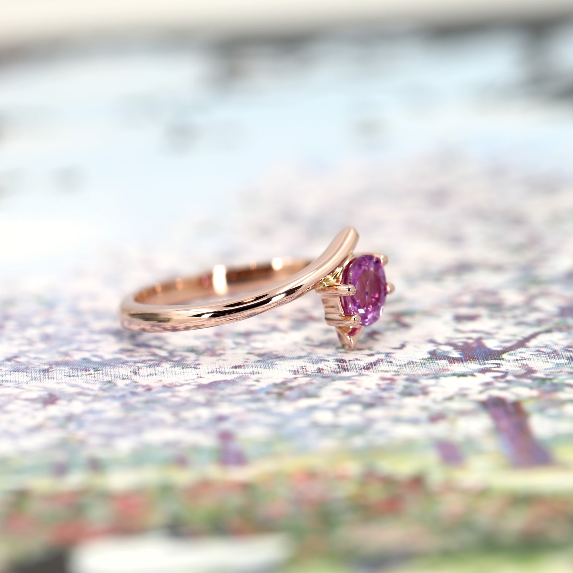 side view of rose gold twist engagement ring custom made in motnreal by bena jewelry on multi color background