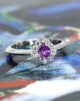 A luxurious engagement ring with a pear-shaped sapphire and diamonds, set in white gold and showcased on a colorful background.