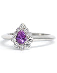 Sleek white gold band supporting a pear-cut pink-violet sapphire, complemented by a radiant halo of diamonds. Handmade in Montreal by independent jewelry designer Bena Jewelry.