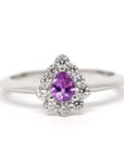 Custom-made bridal ring in white gold, featuring a mesmerizing pink-violet sapphire and diamond halo. Designed and handcrafted in Montreal by Bena Jewelry, a Canadian jewelry designer.