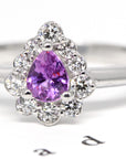 Delicate engagement ring with a pear-cut sapphire and diamond halo, emphasizing the brilliance of its custom-made design. Designed and crafted by Bena Jewelry in Montreal, Canada.