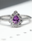 Aura engagement ring featuring a pear-cut pink-violet sapphire with a diamond halo, set in polished white gold. Handmade in Montreal by Bena Jewelry, a Canadian designer.