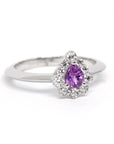 Elegant sapphire and diamond halo ring crafted in white gold, showcasing a custom pear-cut pink-violet sapphire centerpiece. Designed by Bena Jewelry, an independent Canadian jewelry designer in Montreal.