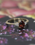 Désir Pyrope Garnet Ring in yellow gold featuring an oval pyrope garnet and diamonds by Bena Jewelry displayed on a vibrant colored background custom-made in Montreal