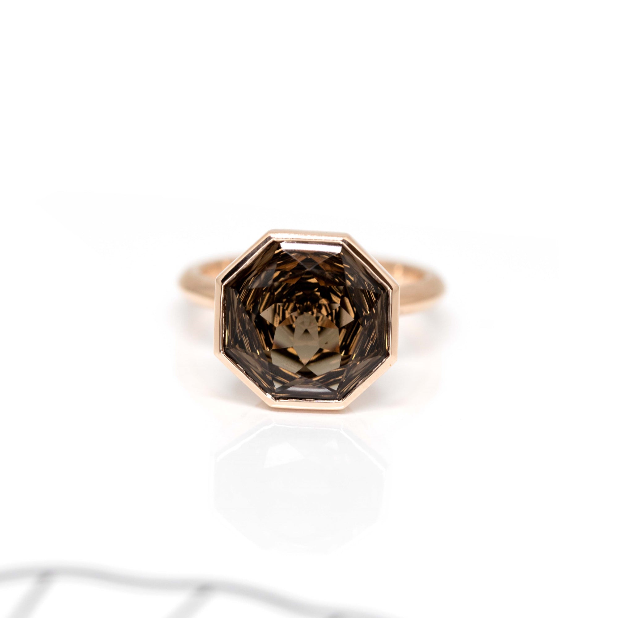 Rose gold cocktail ring with a Brazilian smoky quartz, featuring a round-octagon cut, displayed on a bold white and red background.