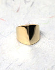 Close-up of gold ring on dark background – The bold structure of the boxy ring stands out against the dark backdrop, highlighting its modern elegance.