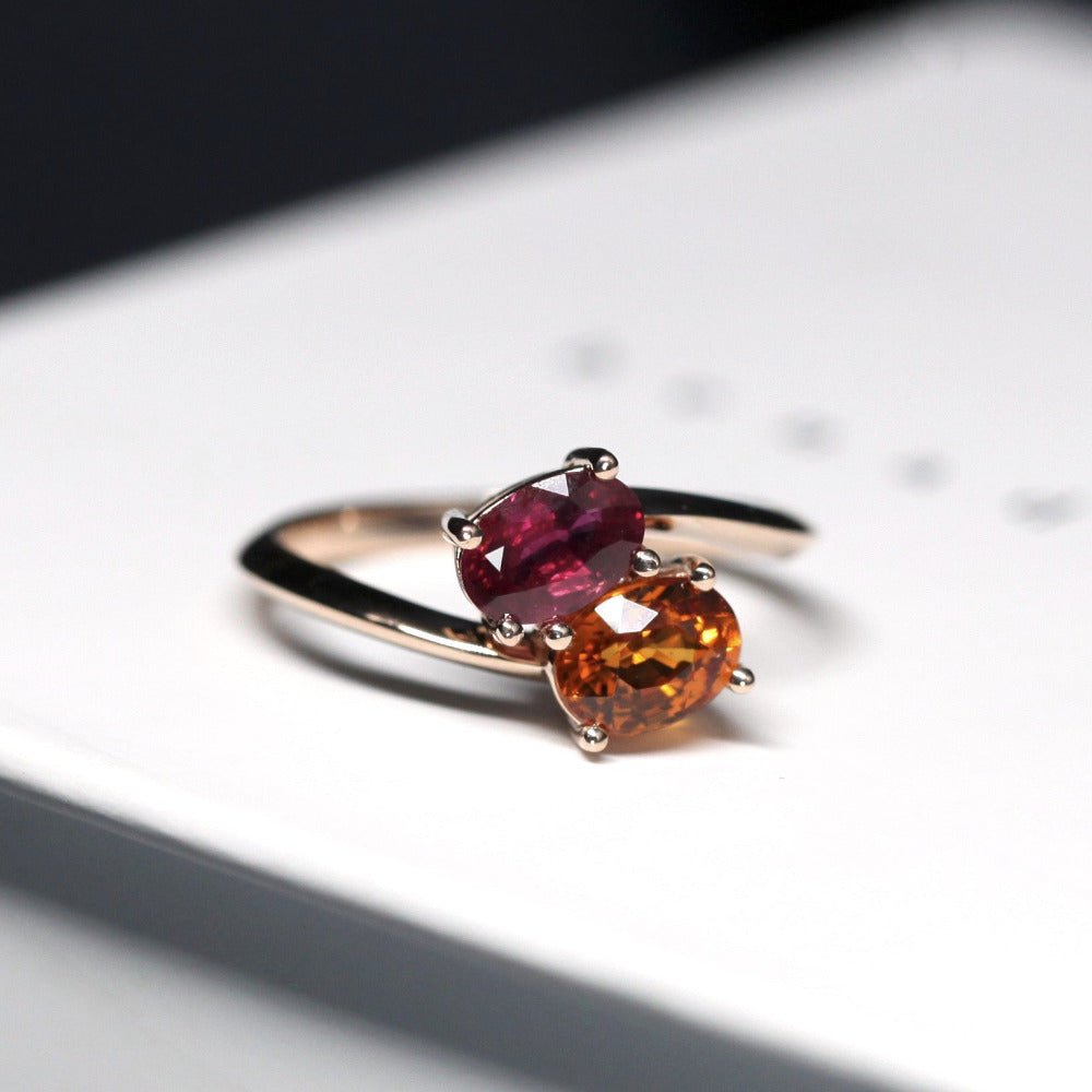 Close-up of ruby and spessartite ring – A striking combination of red and orange gemstones, set in a warm rose gold band.