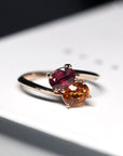 Close-up of ruby and spessartite ring – A striking combination of red and orange gemstones, set in a warm rose gold band.