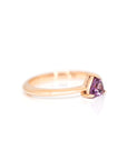 side view of rose gold ring with pink violet trillion garnet gemstone on white background