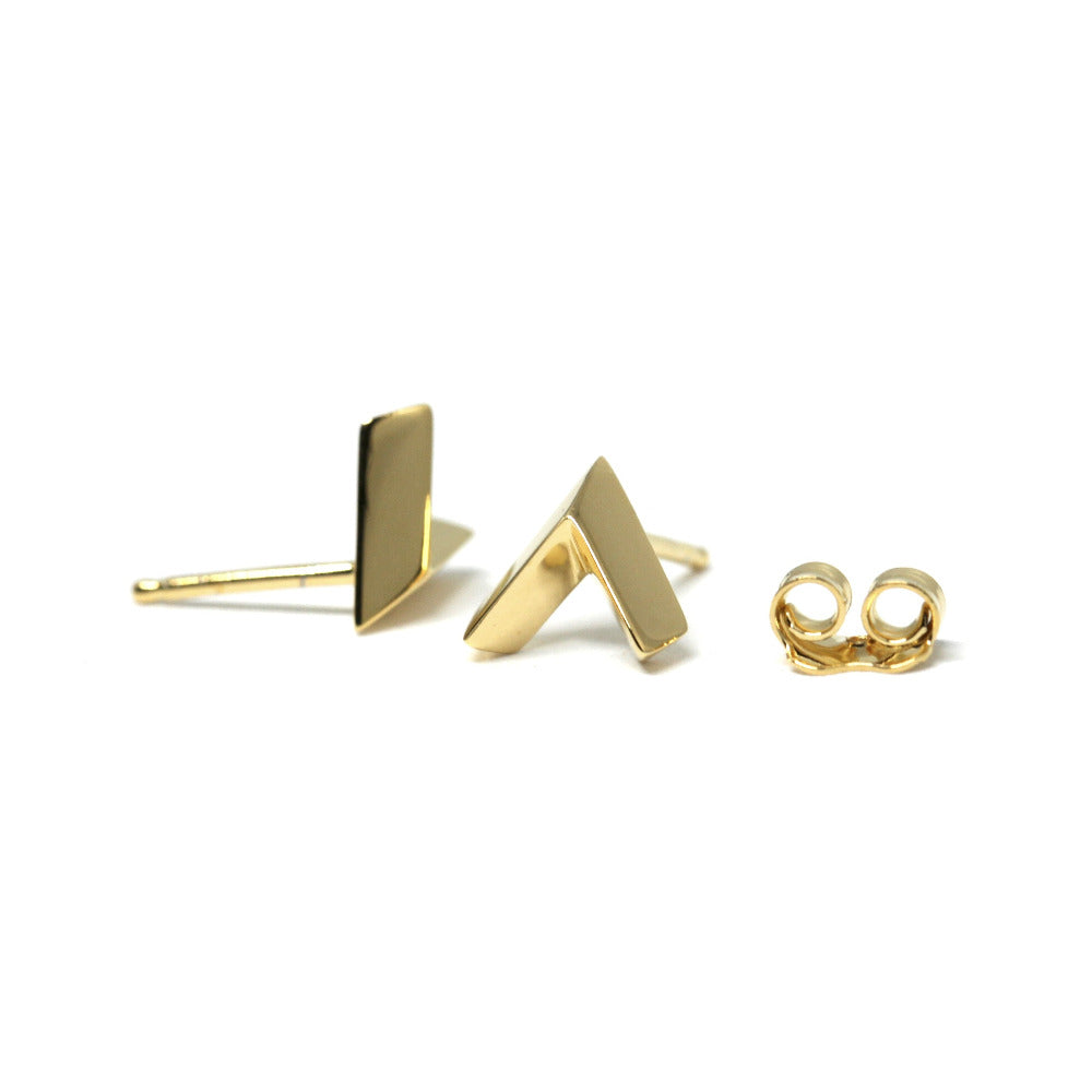 Angled view of a white gold stud in the shape of an arrow, set against a white backdrop. This edgy and modern piece is unisex and created by Bena Jewelry, a Canadian contemporary jewelry designer based in Montreal.