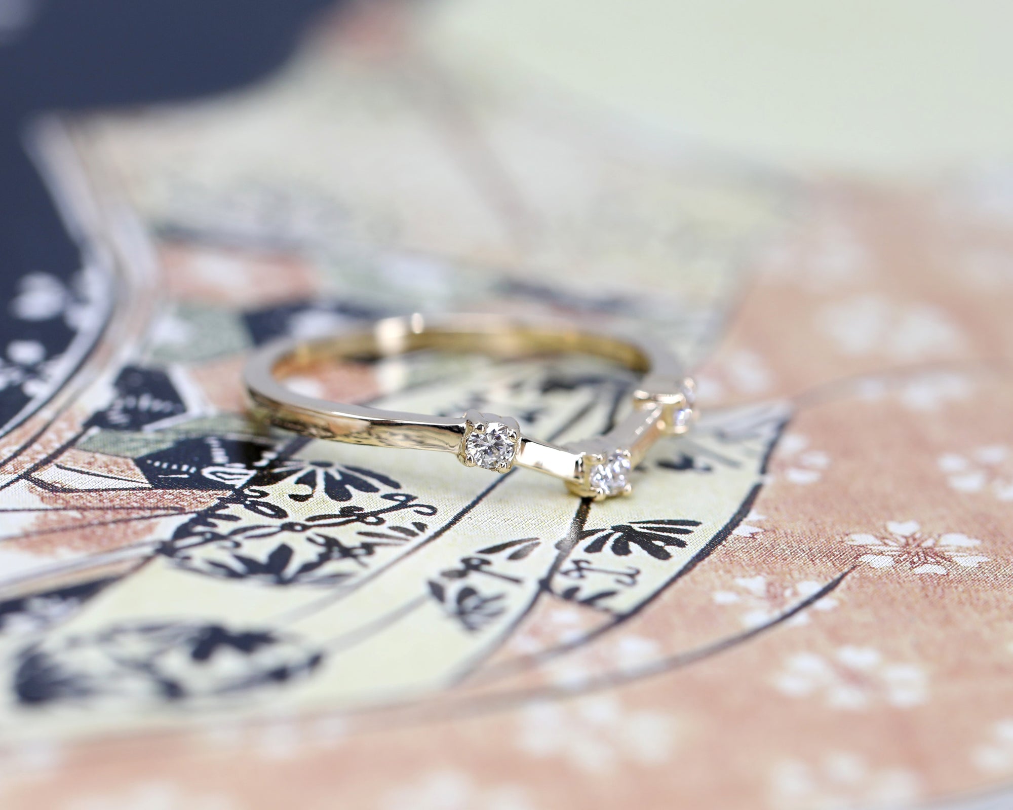 Stylish yellow gold wedding band featuring round diamonds and a bold geometric design. The colored background highlights the ring’s edgy aesthetic. Made in Montreal by Bena Jewelry.
