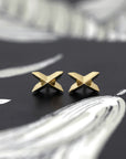 Yellow gold Cross Gold Studs with edgy sharp style by Bena Jewelry, displayed on a black matte background, fine designer earrings from Canada.