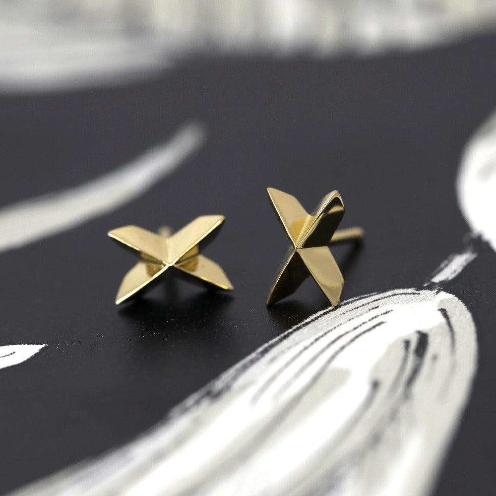 Yellow gold Cross Gold Studs with a voluminous geometric cross shape by Bena Jewelry, displayed on a black background, modern designer earrings made in Canada.