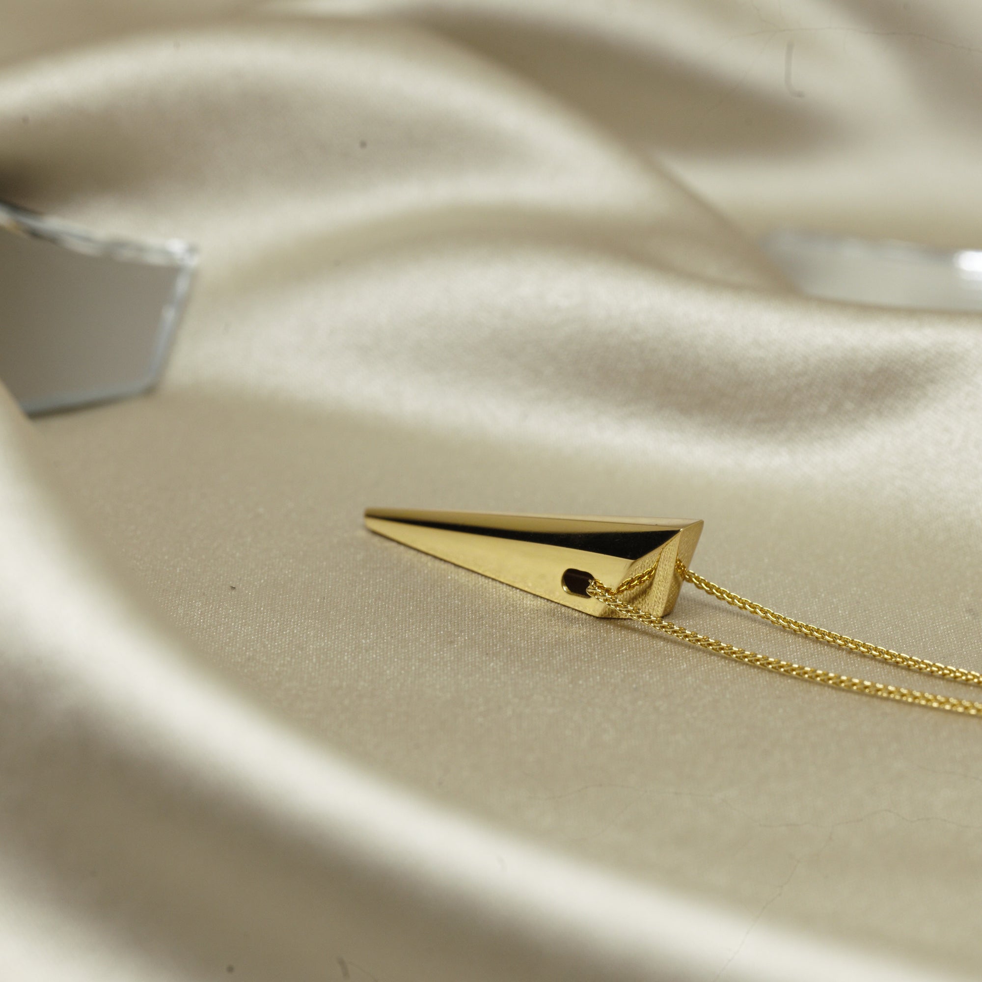 Yellow Gold Pike Pendant displayed on a marble surface – A luxurious fine jewelry piece with an edgy, high-polish finish.