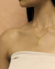 Close-up of Pike Pendant worn at the collarbone – A contemporary gold pendant adding a touch of power and refinement.