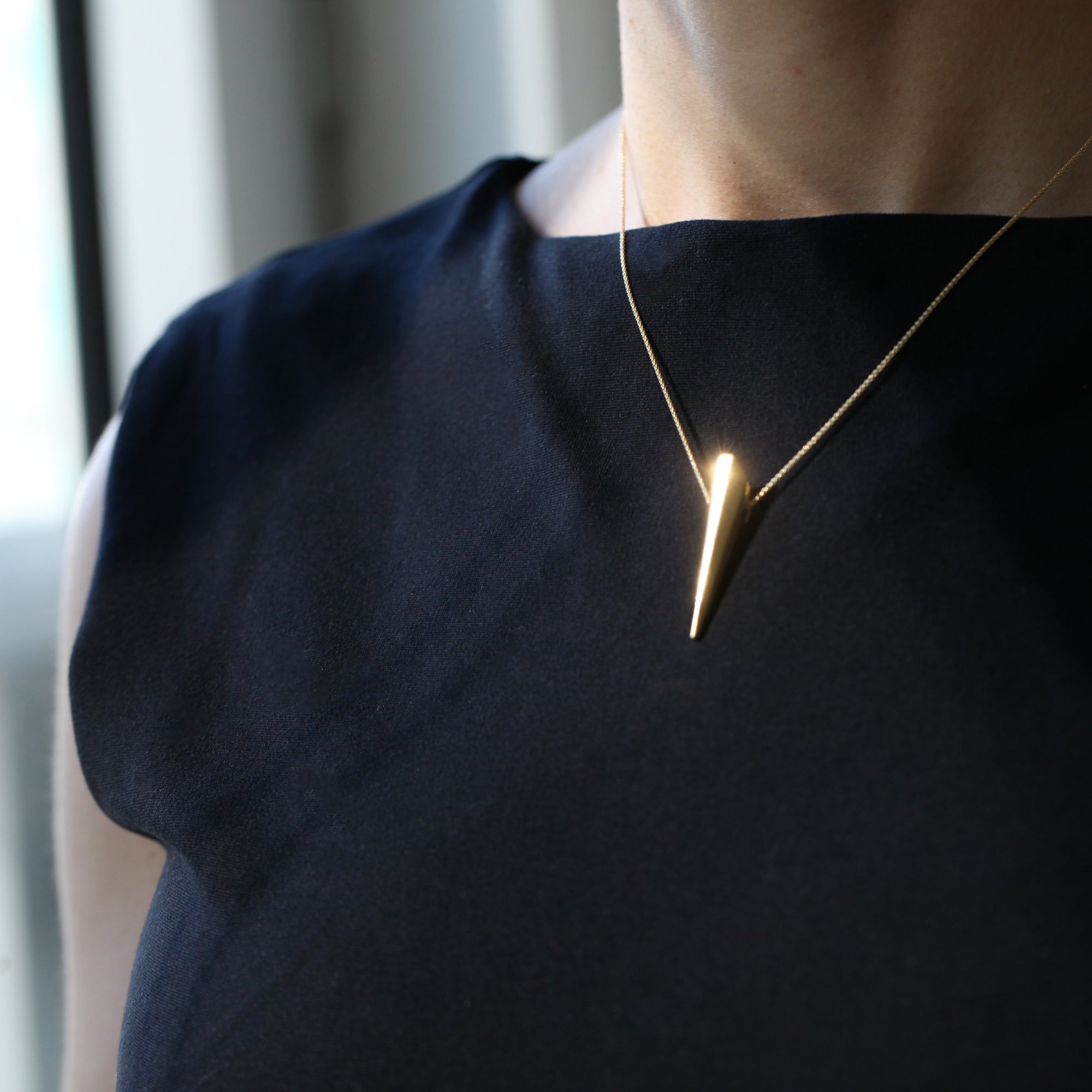 Side view of Pike Pendant on a model’s neckline – A bold yet minimalist piece, designed for everyday elegance.