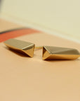 Close-up of gold earrings on dark background – The polished gold finish and bold edges stand out dramatically in this edgy fine jewelry design.