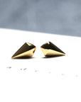 Mini Spade Stud Earrings on soft-toned background – The polished gold finish stands out against a neutral backdrop, emphasizing the clean design.