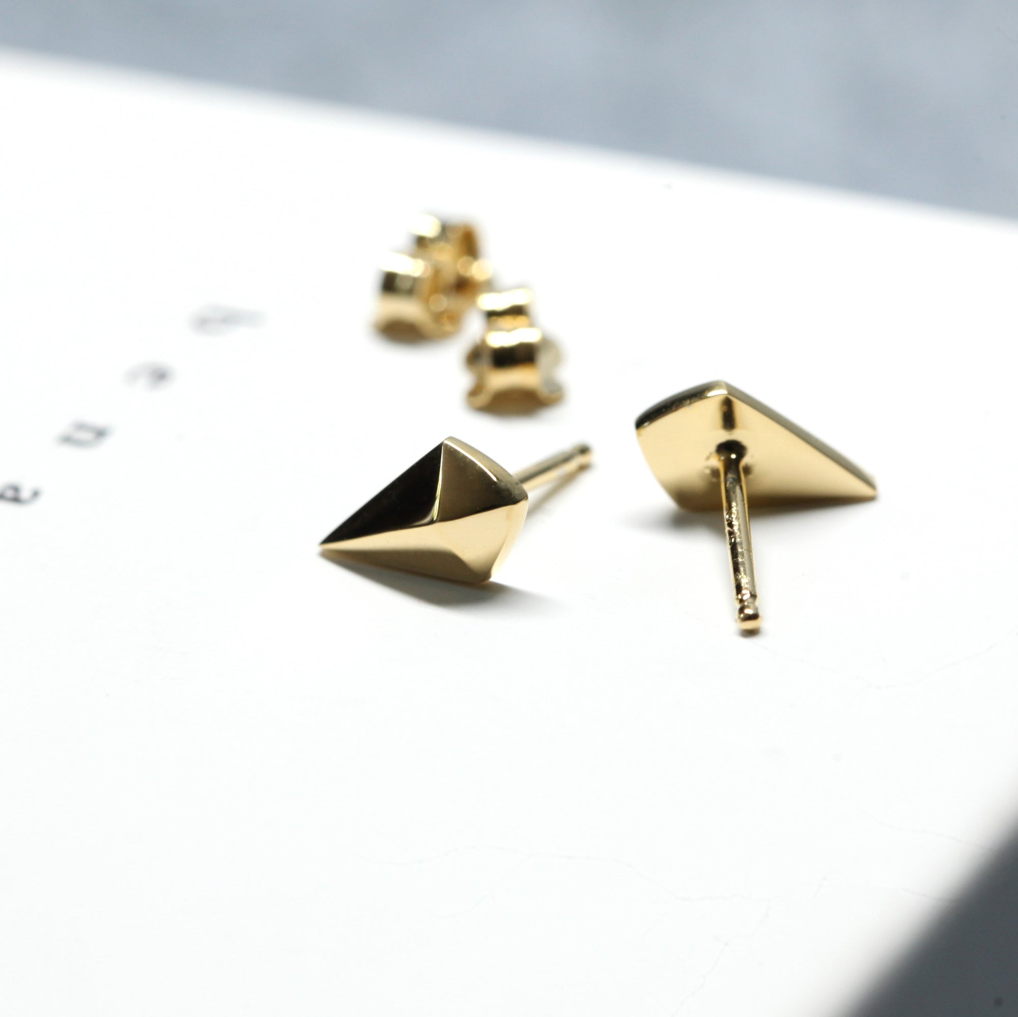 Back view of gold studs on dark background – A sleek and contemporary fine jewelry piece, perfect for understated elegance.