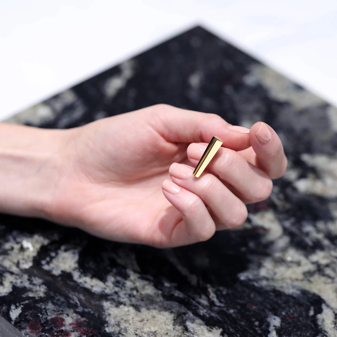 Product photography of the Sturdy ring, a solid gold ring by Bena Jewelry. The high end unisex and minimalist piece of jewellery is seen on a marble background. 