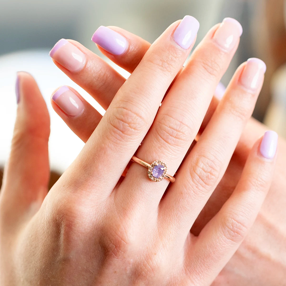 Hand wearing a Bena Jewelry sapphire ring with a lavender opalescent sapphire and champagne diamond halo in rose gold. Independent Canadian designer jewelry from Montreal.